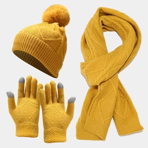 Detail of yellow knit winter set featuring pom-pom hat, scarf, and touchscreen gloves
