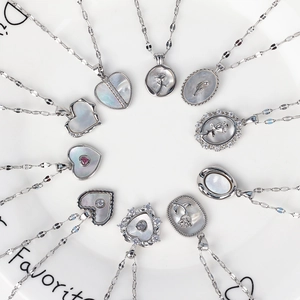 Detailed close-up of various vintage shell necklaces with silver pendants and rose reliefs
