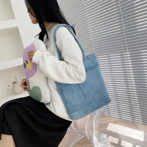 Detail of light blue denim tote bag featuring large front pockets and casual style