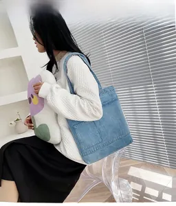 Dettaglio della borsa tote in denim azzurro con grandi tasche frontali e stile casual