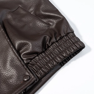 Macro shot of dark brown lychee texture leather jacket with snap button and elastic cuff