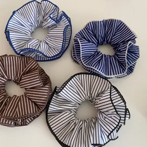 Chouchous en tissu rayé bleu marine, bleu clair et marron sur un fond blanc neutre
