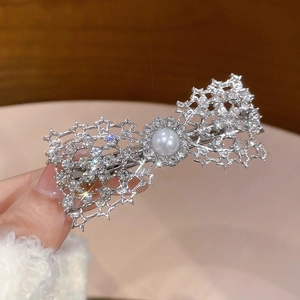 Detailed close-up of hollow star metal bow hair clip with white rhinestones and a pearl