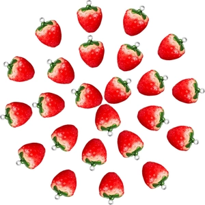 Top view of red resin strawberry charms with green leaves and metal loops for DIY jewelry
