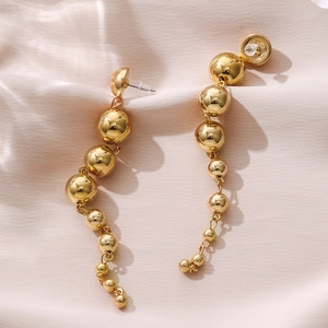 Elegant gold drop earrings with tiered metallic beads on a soft pink silk background
