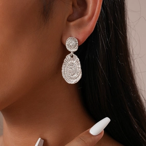 Détail de boucles d'oreilles ovales en argent vintage avec texture spirale sur un mannequin