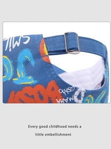 Détail d'une casquette enfant en toile bleue avec boucle en métal réglable et texte coloré