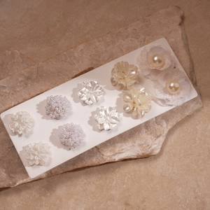 Detail of 10-piece acrylic pearl floral earring set with elegant textures and white flower charms