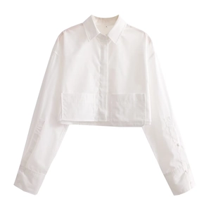 Detail of white long sleeve cropped shirt featuring button closure and two front pockets