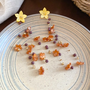Close-up of resin flower earrings with pearls and tassels on vintage ceramic plate