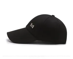 Side view of black baseball cap featuring an elongated brim and silver metal M logo