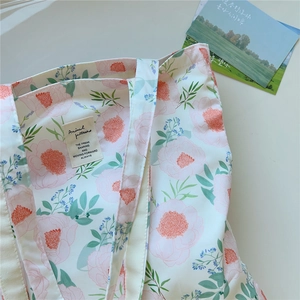 Gros plan sur le sac fourre-tout en coton blanc avec motif floral rose et étiquette tissée
