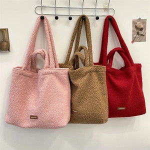 Dettaglio di borse tote in sherpa rosa, marrone e rosso con patch in pelle cucita