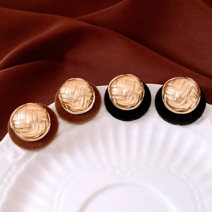 Detail of round vintage earrings with woven metal texture and velvet flocking base