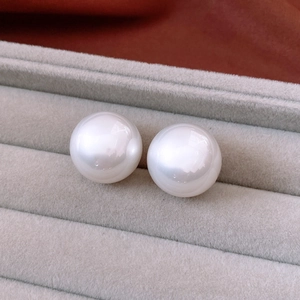 Close-up of high-luster white round pearls showcased in a grey velvet jewelry box