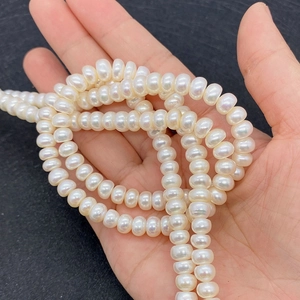 Close-up of hand holding glossy white freshwater pearls for DIY jewelry making
