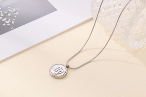 Macro detail of Virgo zodiac shell necklace with circular stainless steel pendant