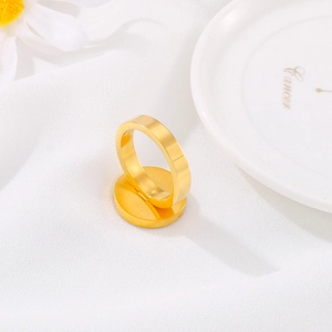 Polished gold stainless steel ring displayed on matching stand with silk and flowers