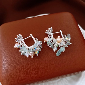 Detailed macro view of silver hoop earrings with freshwater pearls and zircon crystals