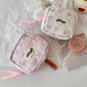 Close-up of pink and white quilted fabric makeup bags with floral and bow patterns