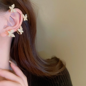 Macro view of gold butterfly ear cuff set with rhinestones on model's ear