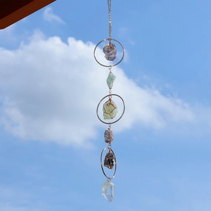 Hanging natural amethyst and citrine suncatcher with metal rings against a blue sky