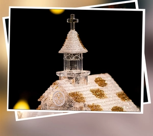 Detailed close-up of a crystal church music box with golden glitters and warm bokeh lights