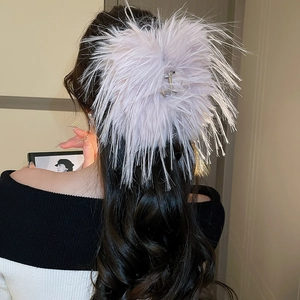 Detailed back view of a large light pink feather hair claw clip on long wavy hair