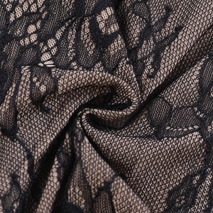 Close-up detail of black lace fabric with nude lining showing intricate floral embroidery patterns