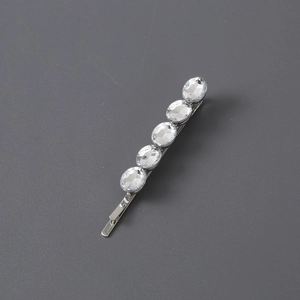 Detail of silver hair clip with five sparkling crystal rhinestones on a dark background