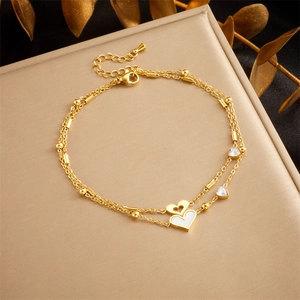Detail of double-layer gold anklet featuring heart charms and tree of life pendants
