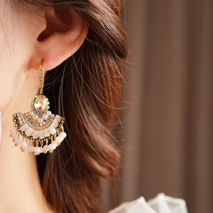 Gros plan d'une boucle d'oreille vintage à pompon éventail avec zircon et perles blanches