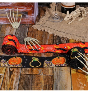 Detail of Halloween spider web and pumpkin printed ribbons on rustic wood table decor