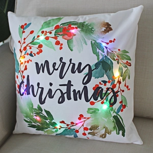 Detail view of glowing LED Christmas pillow with colorful wreath and Merry Christmas text