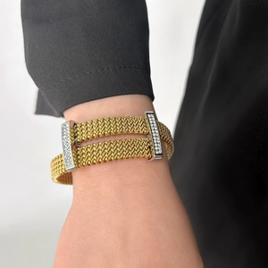 Detail view of a gold mesh wrap bracelet with silver rhinestone clasps on a wrist