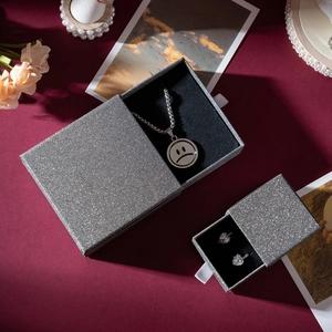 Silver glitter drawer jewelry boxes for necklaces and earrings on dark red background