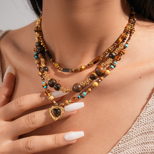 Detail of layered tiger eye beaded necklace with a vintage heart pendant and gold accents