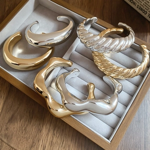 Close-up of irregular minimalist open bangles in gold and silver finish in a display box