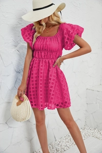 Gros plan sur la texture à carreaux rose d'une mini robe d'été à manches bouffantes