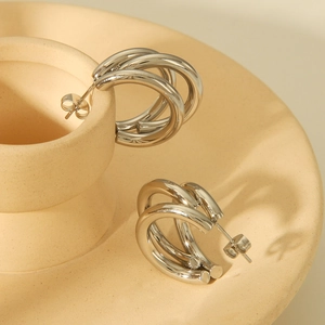 Detail of silver triple hoop earrings with a polished finish on a beige display stand