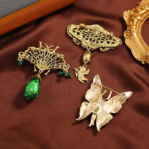 Vintage gold emerald butterfly and bee brooches set showing pin details on brown silk