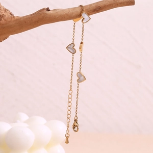 Macro shot of 18K gold plated heart bracelet with white mother-of-pearl shells on wood