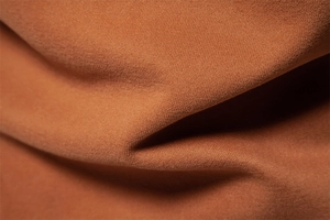 Macro view of brown knitted cotton fabric texture and soft shadow folds on Polo sweatshirt