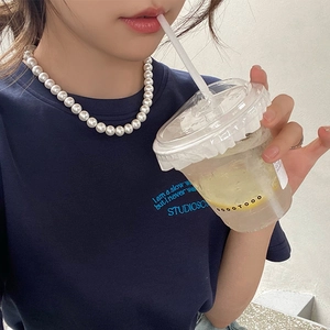 Close-up of elegant pearl necklace worn with casual navy blue printed t-shirt on a model