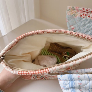 Close-up of a quilted floral and red checkered cotton makeup bag with accessories