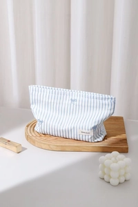Détail d'une trousse à maquillage à rayures bleues et broderie nœud sur bois