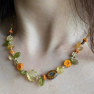 Colorful floral beaded necklace with orange and green petals worn on a female neck