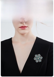 Detailed view of a silver snowflake brooch with blue crystals on a black suit jacket