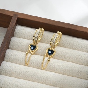 Detail of gold heart earrings with blue gemstones, cubic zirconia and delicate tassels