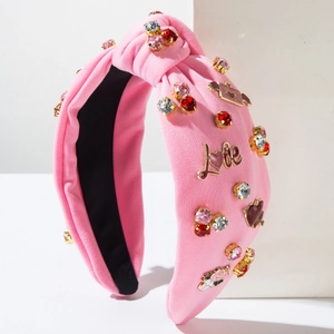 Dettaglio della fascia in maglia rosa con strass scintillanti e scritta Love dorata